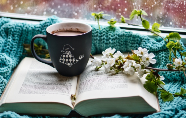 Цветущая ветка вишни на столе с книгой и чашкой кофе