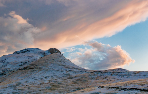 Красивые серые облака над заснеженной горой 