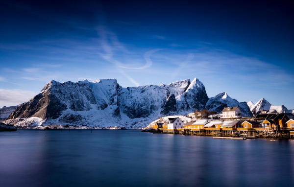 Красивый вид на дома у заснеженных гор под голубым небом 