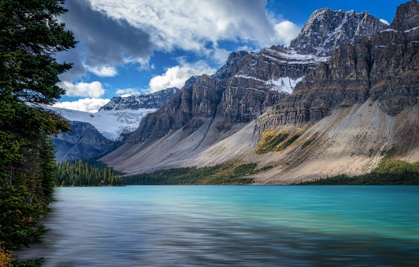 Высокие каменные горы в снегу под голубым небом у озера 