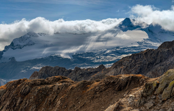 Густые белые облака над заснеженными Альпами
