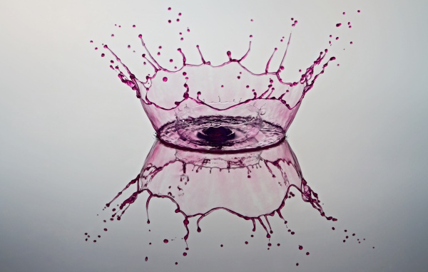 Брызги фиолетовой краски на сером фоне 