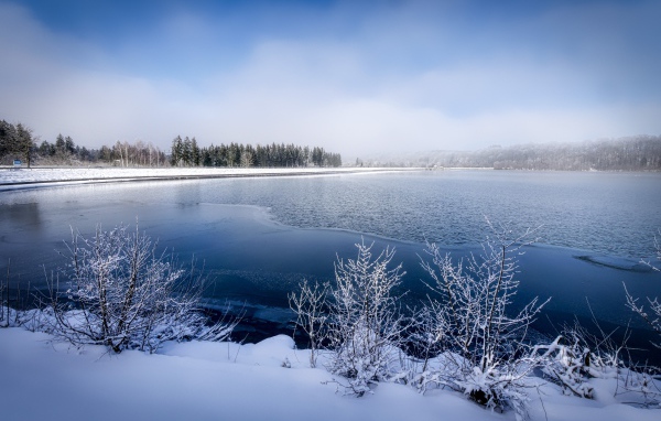 Покрытая льдом река  с заснеженными берегами зимой