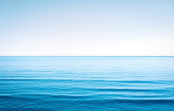 Спокойная голубая морская вода под голубым небом 