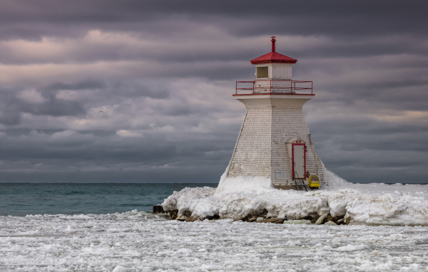 Маяк на покрытом льдом берегу у моря