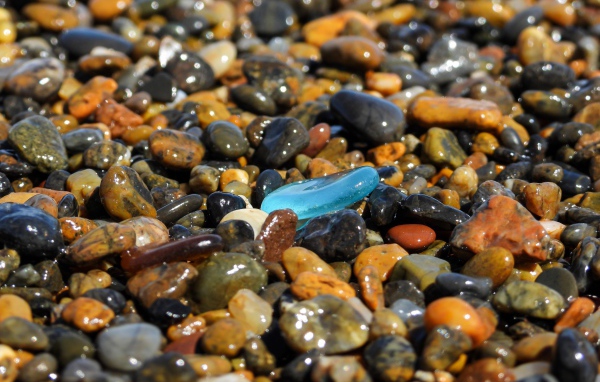 Гладкие разноцветные мелкие камни на пляже 