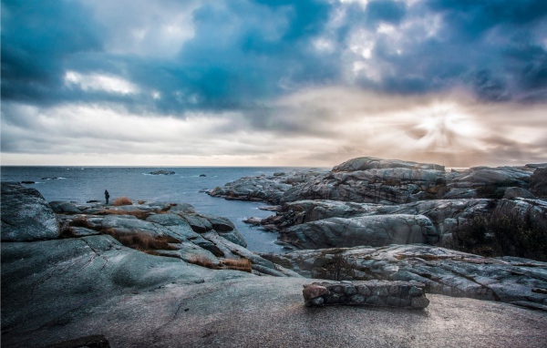 Stone coast by the calm sea under black clouds Desktop wallpapers 600x382