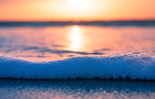 Белая морская пена с пузырям на закате