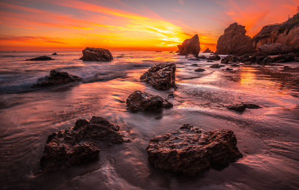 Красивый закат солнца на берегу моря с камнями 