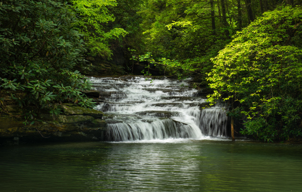 Водопад стекает по каменному каскаду в реку 
