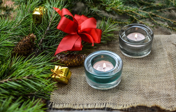 Две зажженные свечи, еловая ветка и красный бант на рождество 