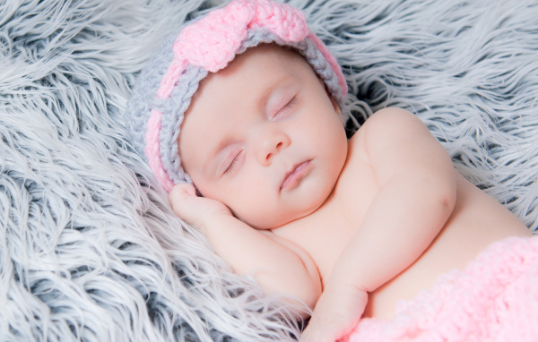 Грудной ребенок спит на меховом одеяле 