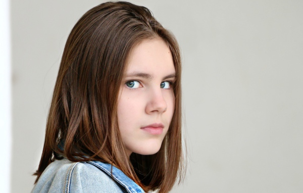 Красивая зеленоглазая девочка на сером фоне