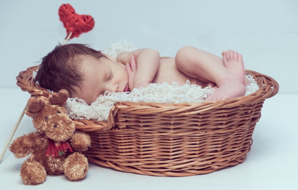 Красивый маленький грудной ребенок спит в корзине с игрушкой 