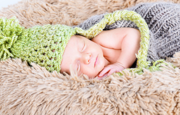 Красивый спящий грудной ребенок в вязаном костюме 