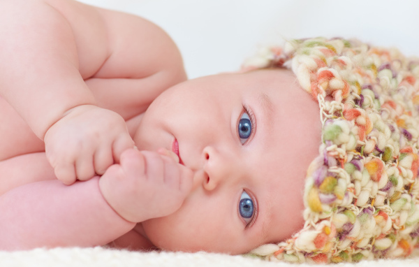 Голубоглазый грудной ребенок в шапке 