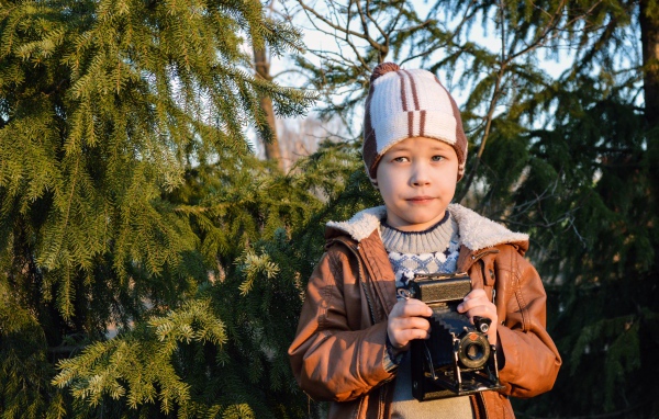 Мальчик с фотоаппаратом у ели