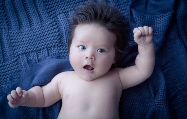 Мальчик с густыми волосами на синем покрывале 