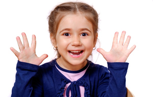 Веселая маленькая девочка с поднятыми руками