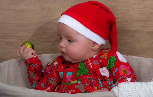 Ребенок в новогодней шапке с игрушкой в руке