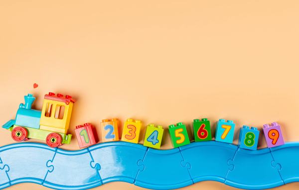 Детский игрушечный паровоз на бежевом фоне 