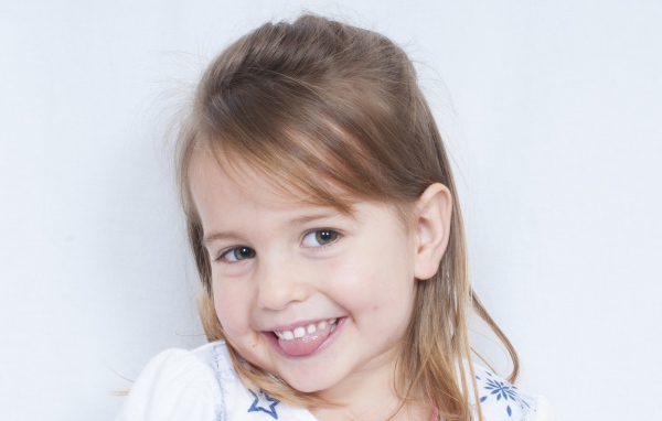 Милая улыбающаяся девочка с высунутым языком