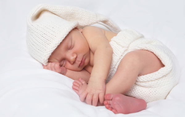 Нежный новорожденный ребенок в белом костюме