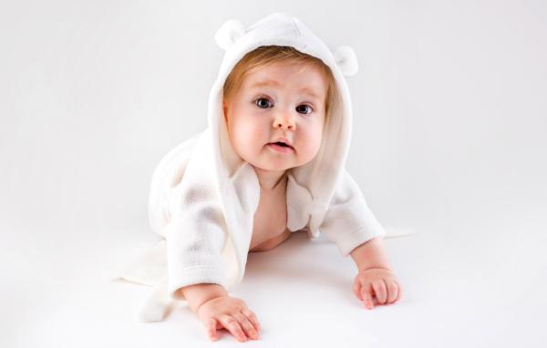 Забавный малыш ползает в белом наряде 
