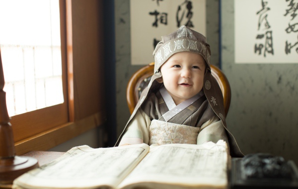 Маленький азиатский мальчик за столом с книгой