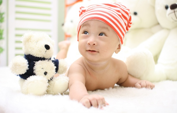 Маленький мальчик азиат на кровати с игрушкой