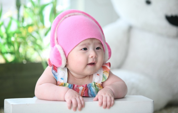 Маленький ребенок азиат в розовой шапке 