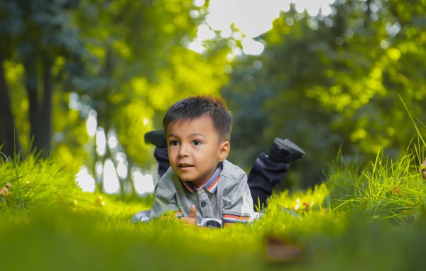 Маленький мальчик лежит на зеленой траве 