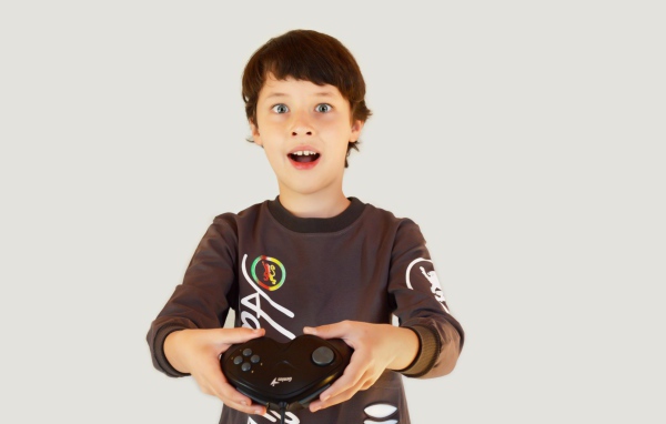 Маленький мальчик с приставкой на сером фоне 