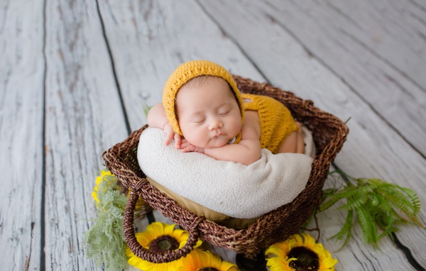 Маленький ребенок спит в плетеной корзине 