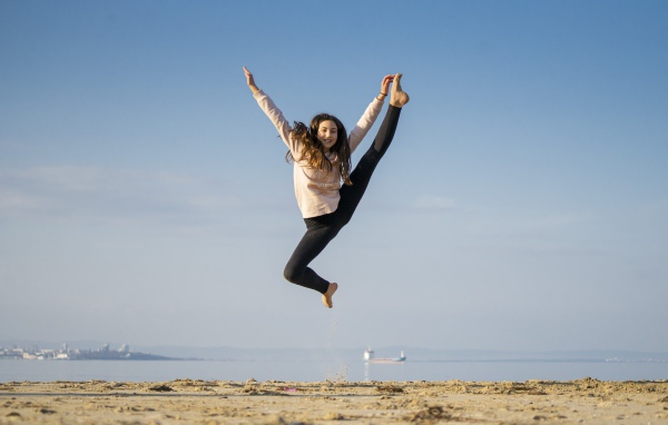 Маленькая девочка гимнастка на песке