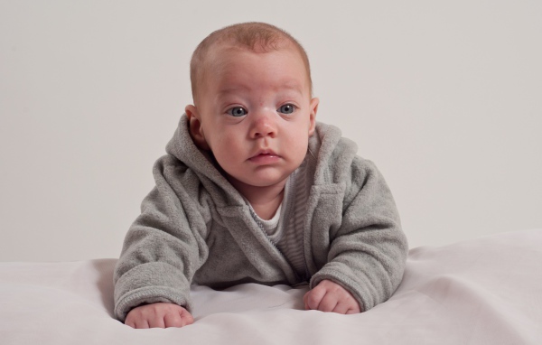 Маленький новорожденный мальчик в сером костюме