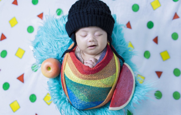 Маленький спящий ребенок в черной шапке 