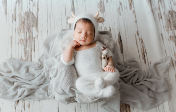 Маленький спящий грудной ребенок в белом костюме