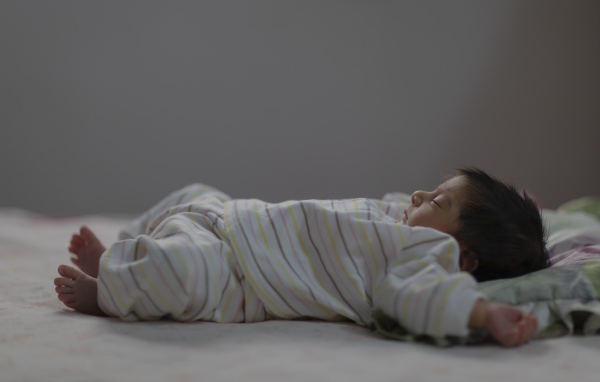 Маленький спящий грудной ребенок на кровати 