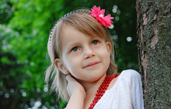 Маленькая улыбающаяся девочка у дерева 