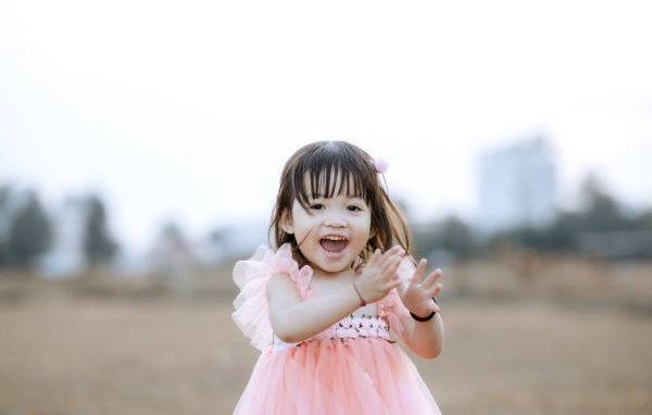 Довольная маленькая девочка в розовом платье 