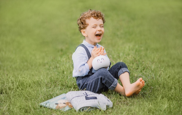Улыбающийся мальчик сидит на траве