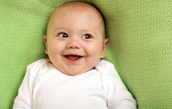 Улыбающийся маленький ребенок на зеленом покрывале 