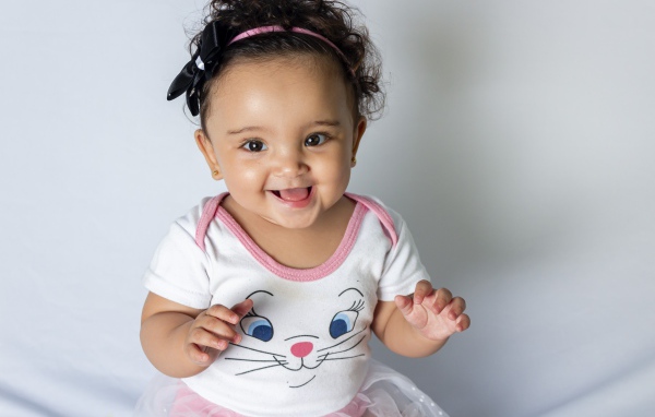 Улыбающаяся маленькая девочка на сером фоне 