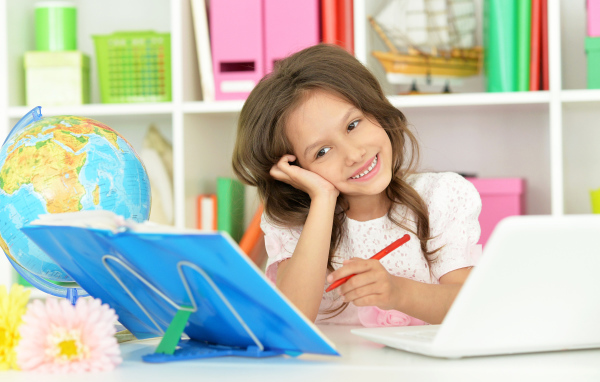 Улыбающаяся девочка ученица делает уроки 