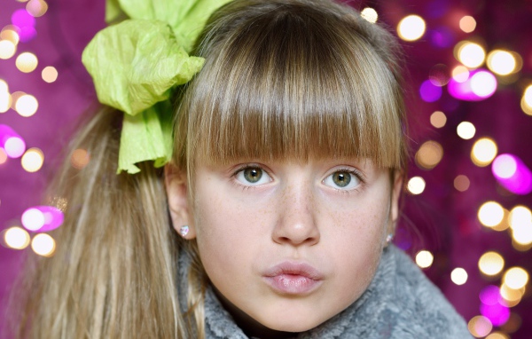 Лицо зеленоглазой девушки с бантом на голове 