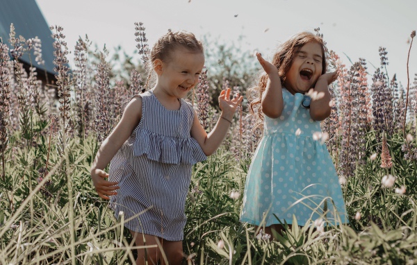 Две маленькие веселые девочки в цветах 