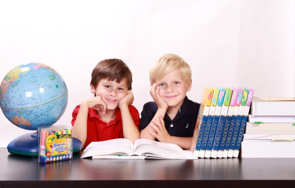 Два школьника за партой с книгами и глобусом 