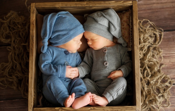 Два маленьких грудных ребенка спят в деревянном ящике