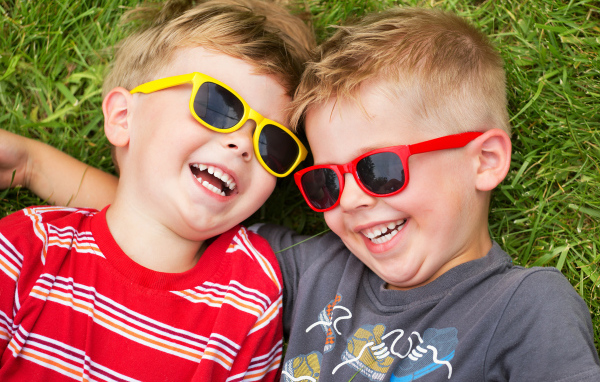 Два улыбающихся мальчика в очках на зеленой траве 